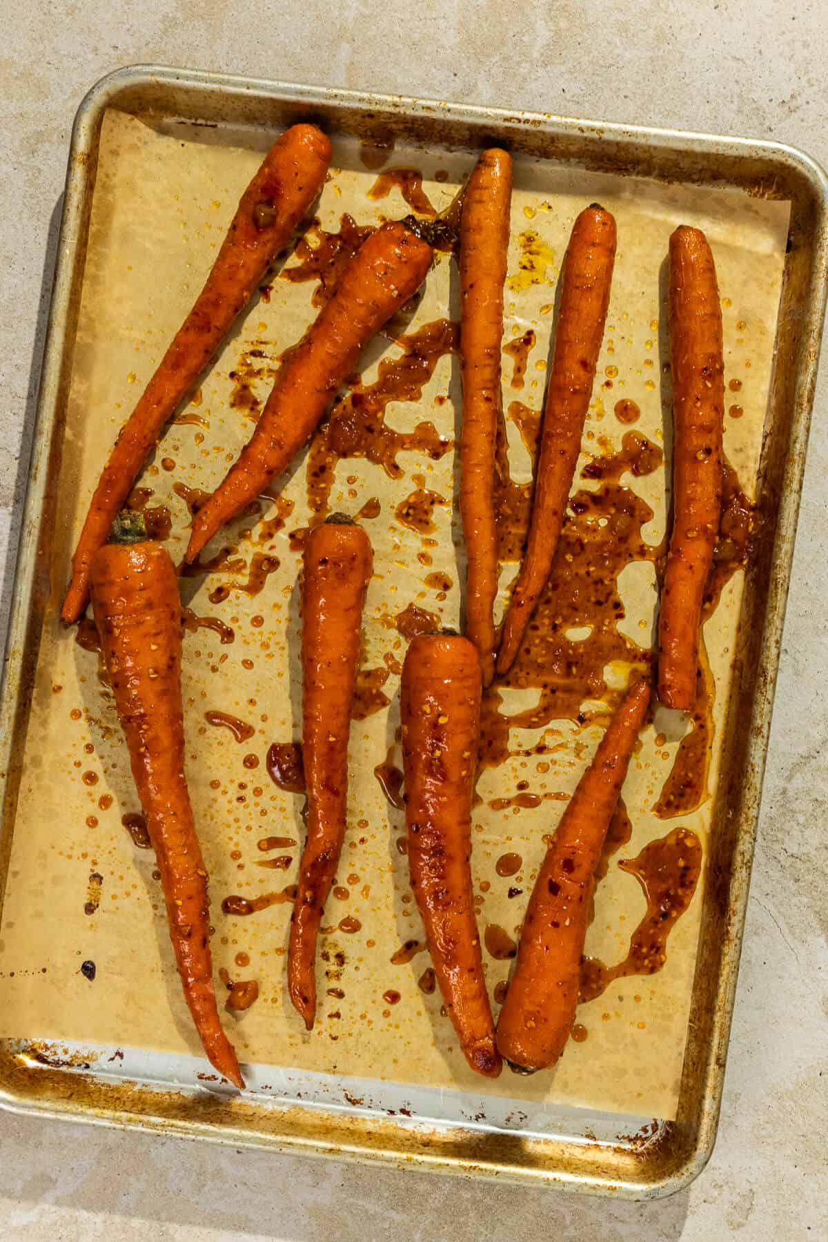 Parchment lined baking sheet with roasted carrots tossed in the apricot chili glaze.