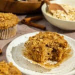 Cinnamon streusel muffin on a plate with a bite taken out of it.