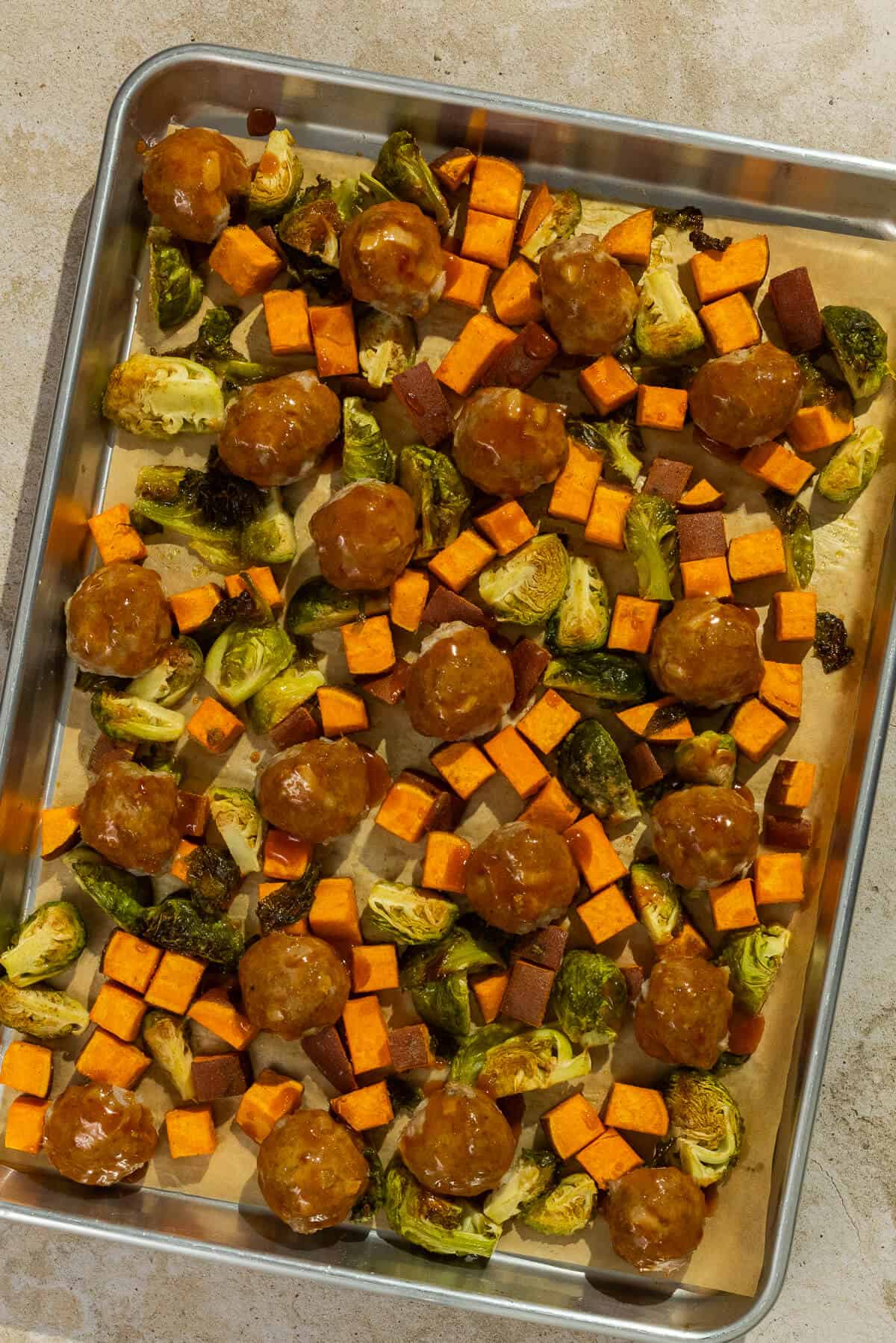 Sheet pan with glaze added to the tops of the meatballs.