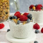 A cup of chia pudding with yogurt topped with berries and granola.