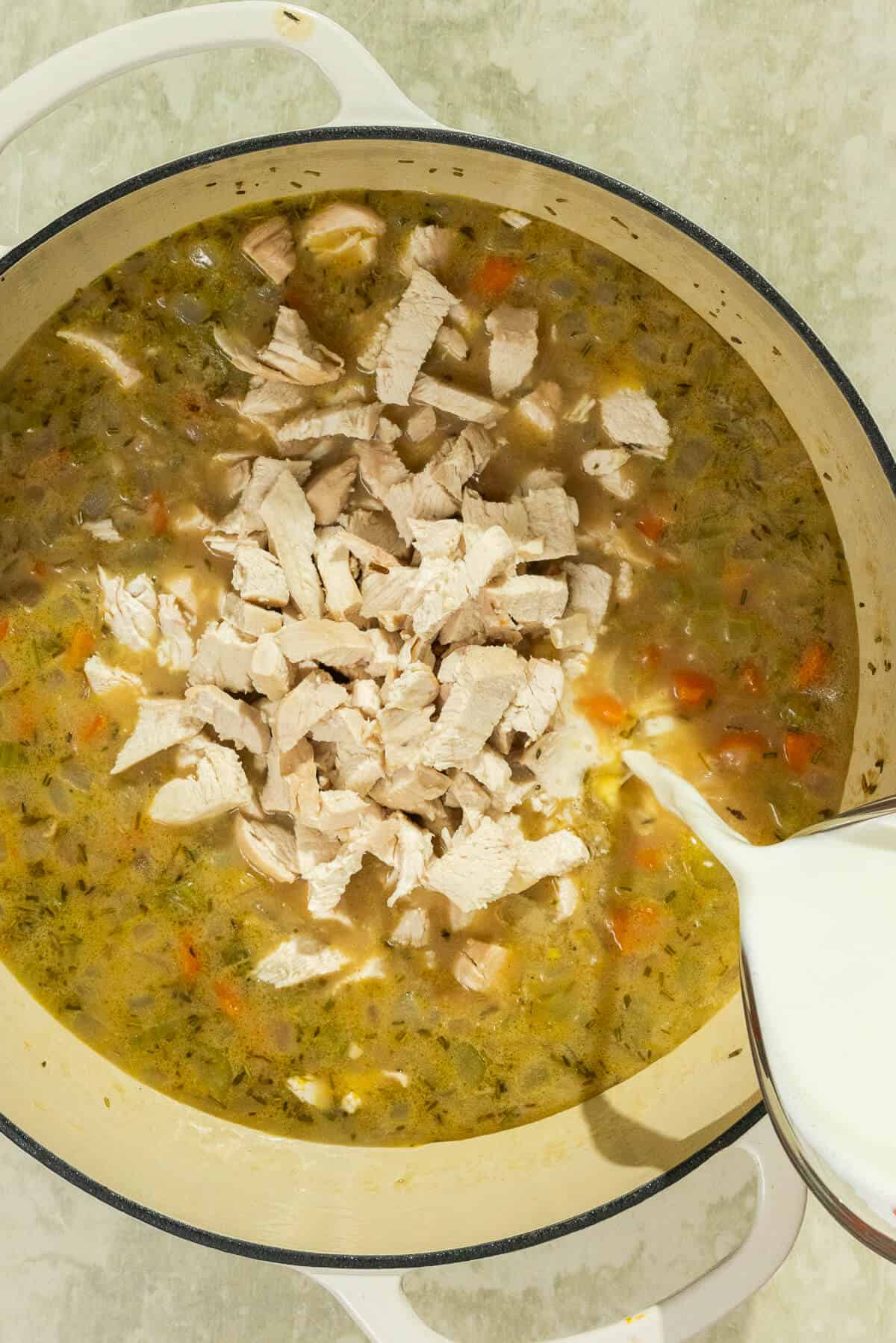 Milk being poured into the pot of soup.