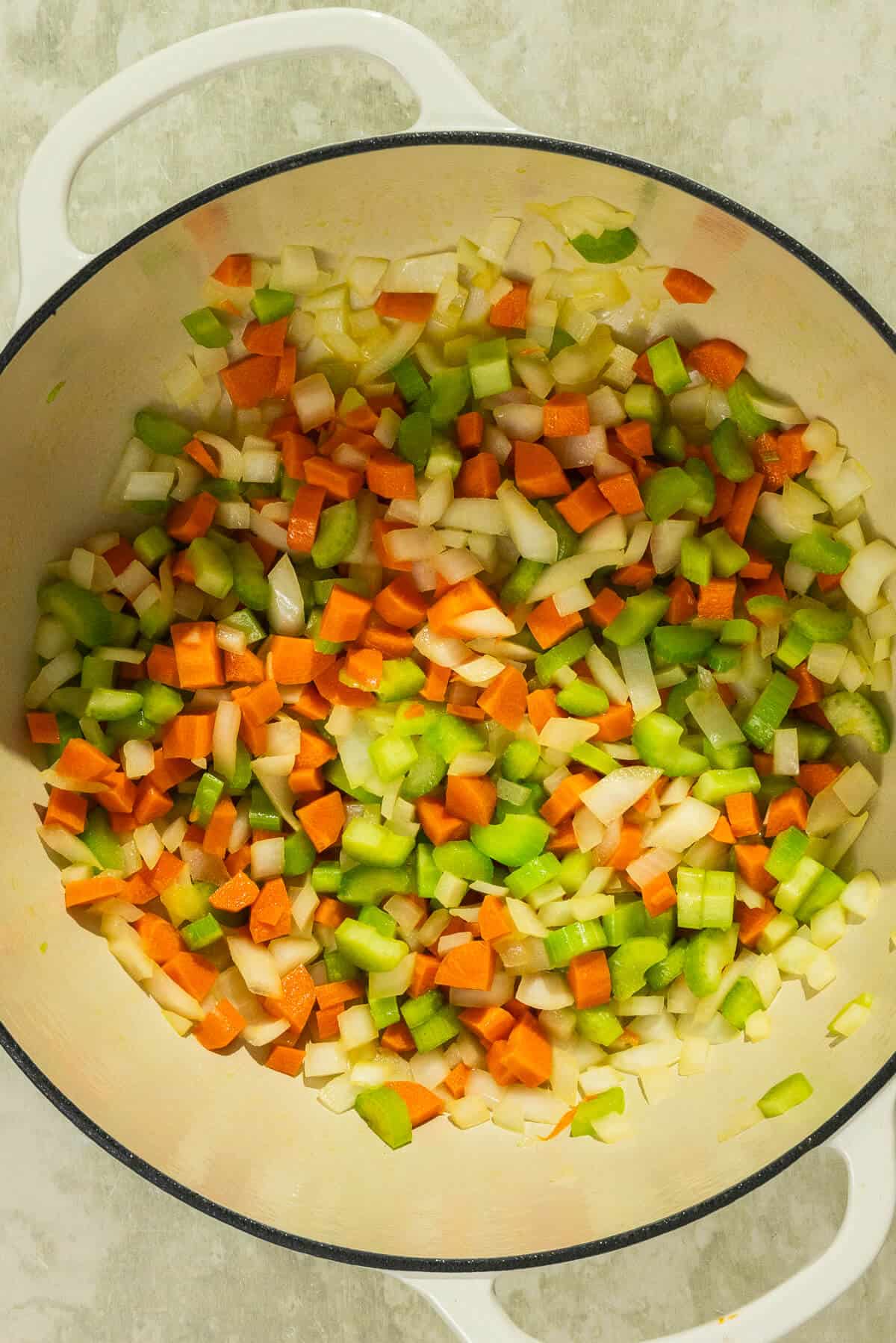 A large pot with diced onion, carrot, and celery.