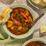 A bowl of crockpot beef stew served with crusty bread.