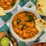 A bowl of butternut squash and chickpea curry served alongside naan.