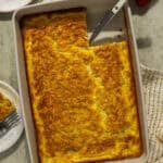 A baking dish with cooked cottage cheese and egg casserole with green chiles that has a square removed.