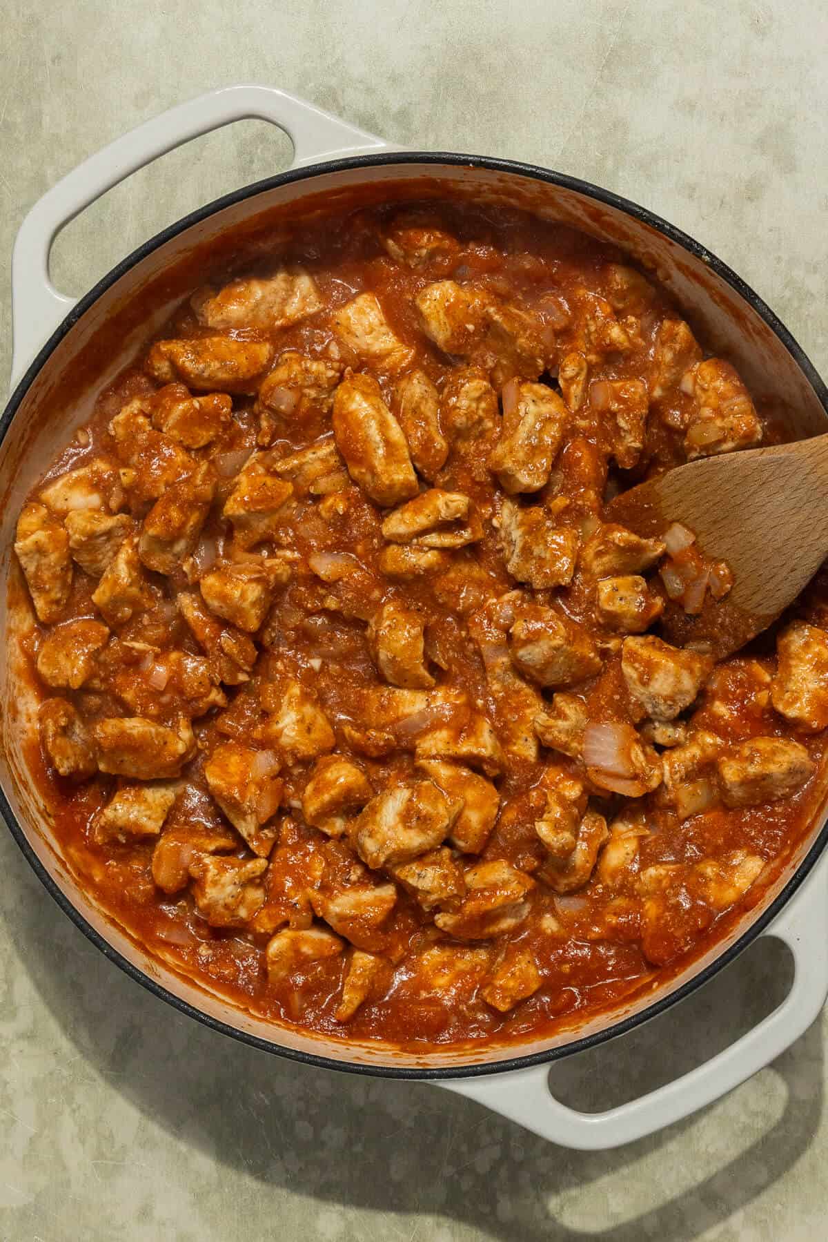 The cooked chicken pieces combined with the butter chicken sauce.