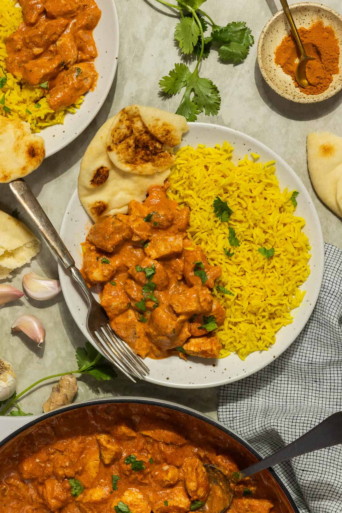 A plate with turmeric rice, butter chicken, and naan.