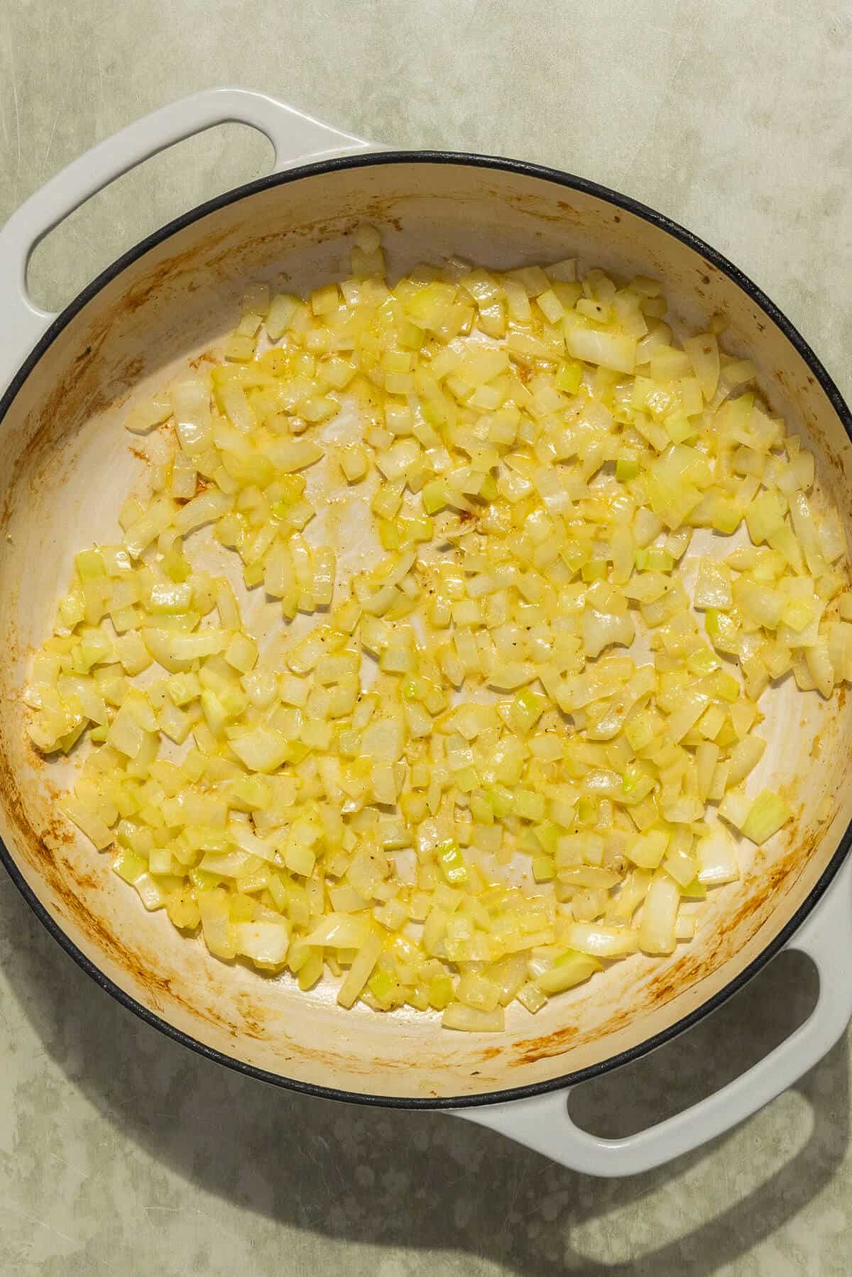 A large skillet with cooked diced onion.