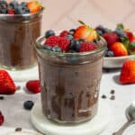 A glass jar of chocolate chia pudding topped with berries.