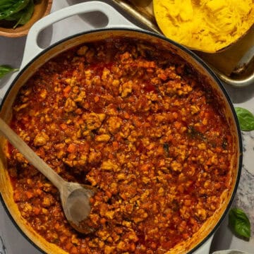 A large skillet of meat sauce next to the roasted spaghetti squash.