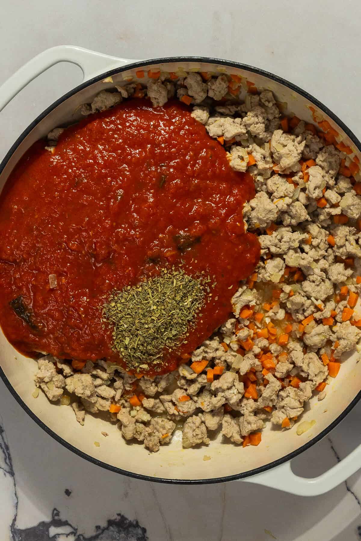 Spices and marinara sauce added to the cooked ground meat and vegetables.