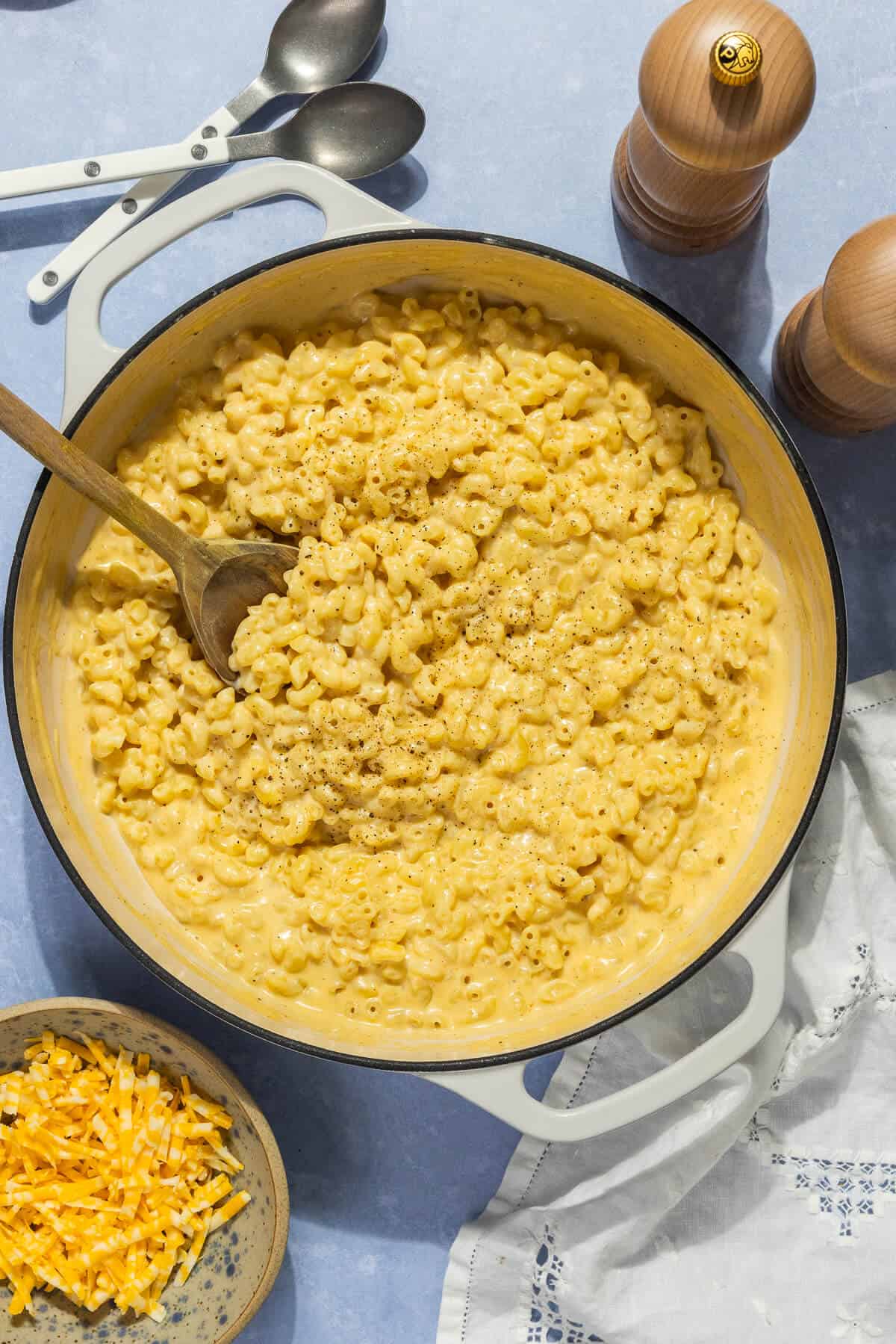 A wooden spoon in a large pot of homemade Mac and cheese.