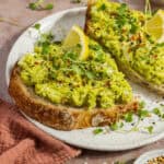 Avocado egg salad spread on toasted bread and topped with lemon and micro greens.