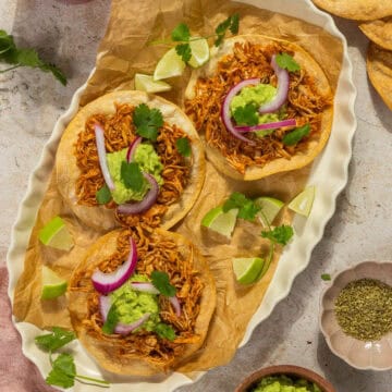 An oval platter with three chicken tinga tostadas.