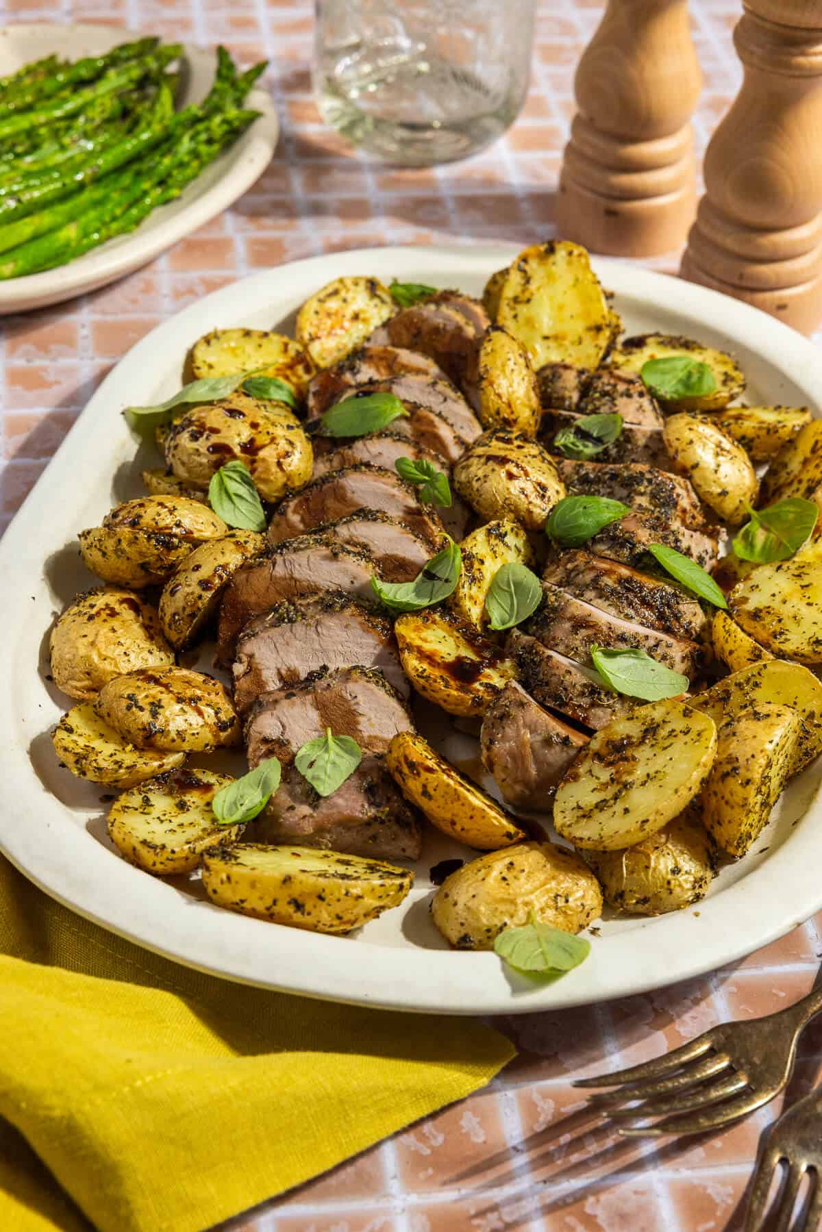 A platter with sliced sheet pan pork tenderloin and roasted potatoes.