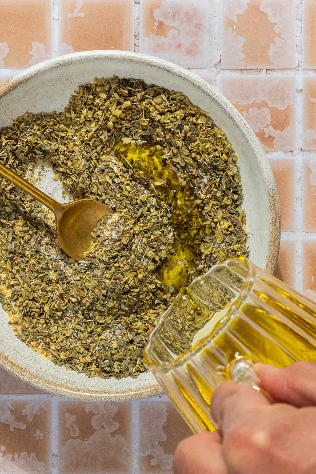Oil being poured into a small bowl of spices.