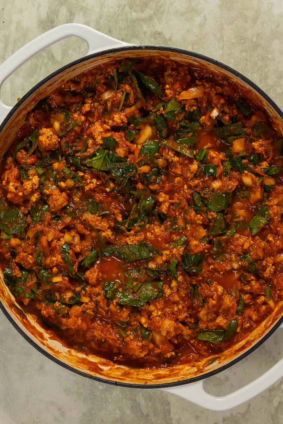 A large skillet with cooked ground turkey, vegetables, spices, and marinara sauce for the lasagna.