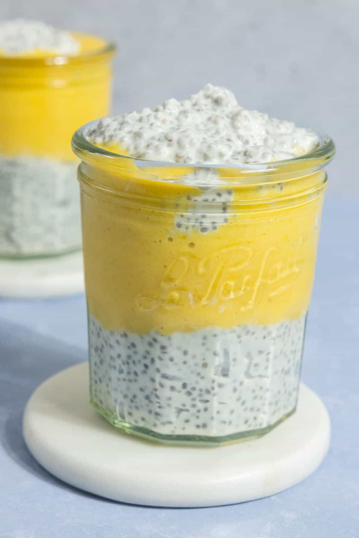 A glass jar with layered mango chia pudding.