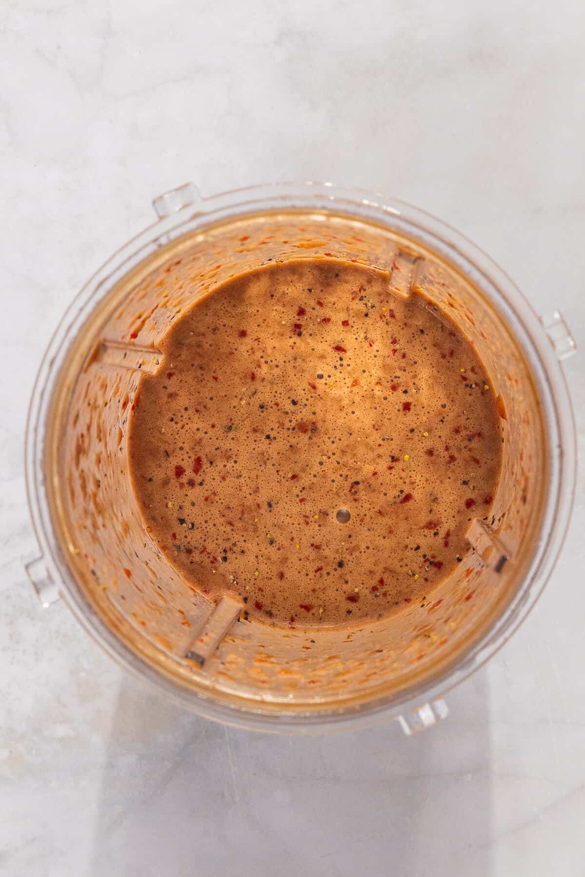 A handheld blender with blended ingredients for a strawberry balsamic vinaigrette.