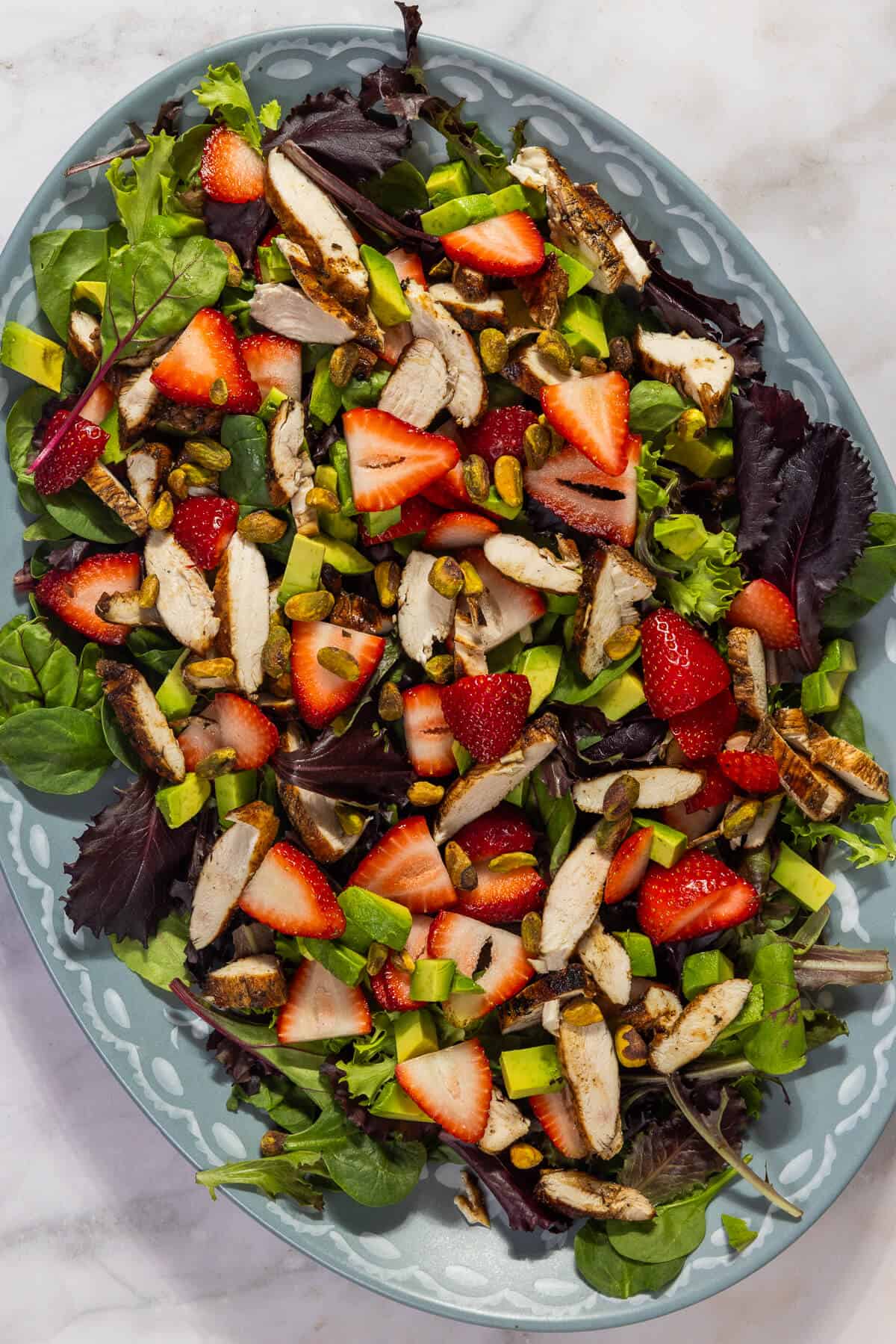 A large platter with strawberry pistachio salad with chicken.