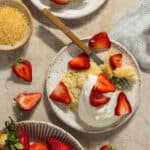 Two plates with shortcake topped with whipped cream and fresh strawberries.