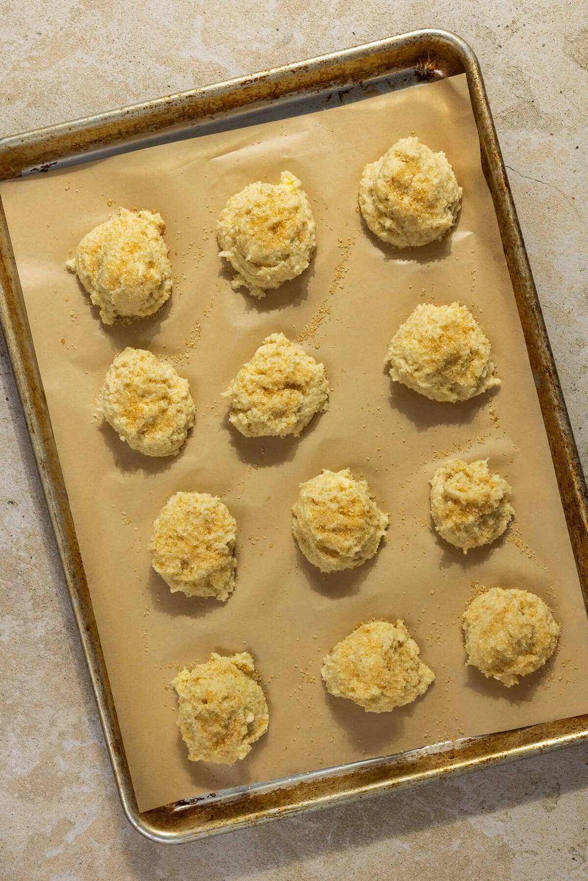 Twelve shortcakes on a parchment lined baking sheet prior to baking.