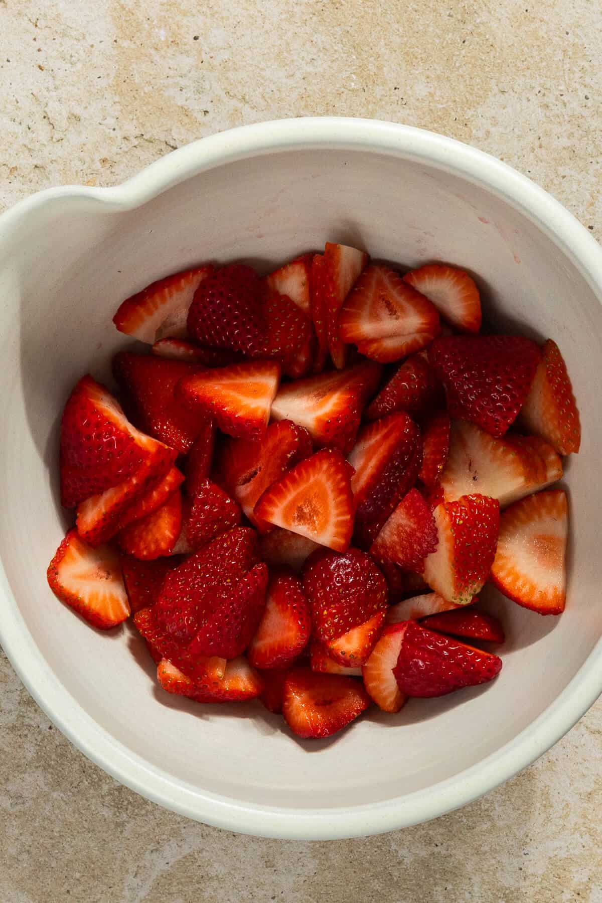 A mixing bowl of sliced strawberries.