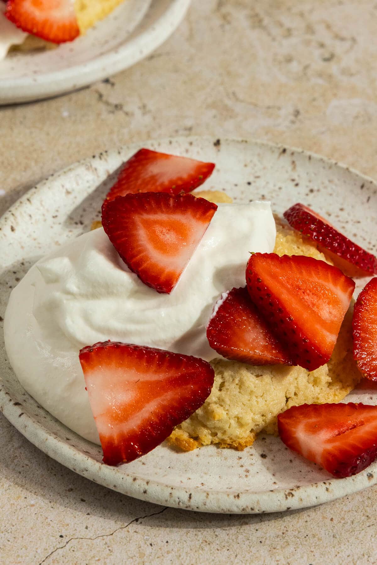 A plate of strawberry shortcake on biscuits topped with whipped cream and fresh strawberries.