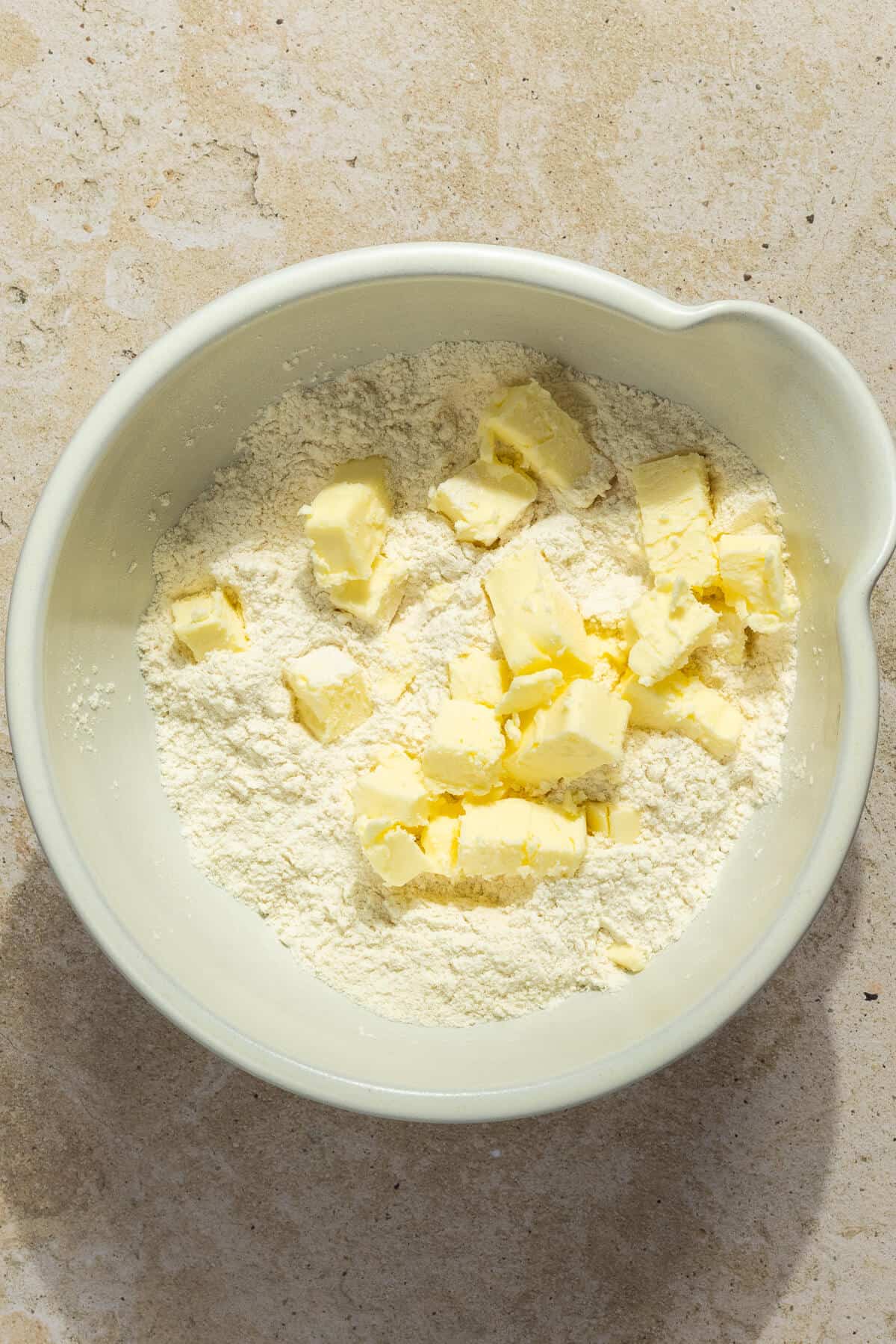 Small cubes of cold butter in a mixing bowl with the dry ingredients prior to combining.
