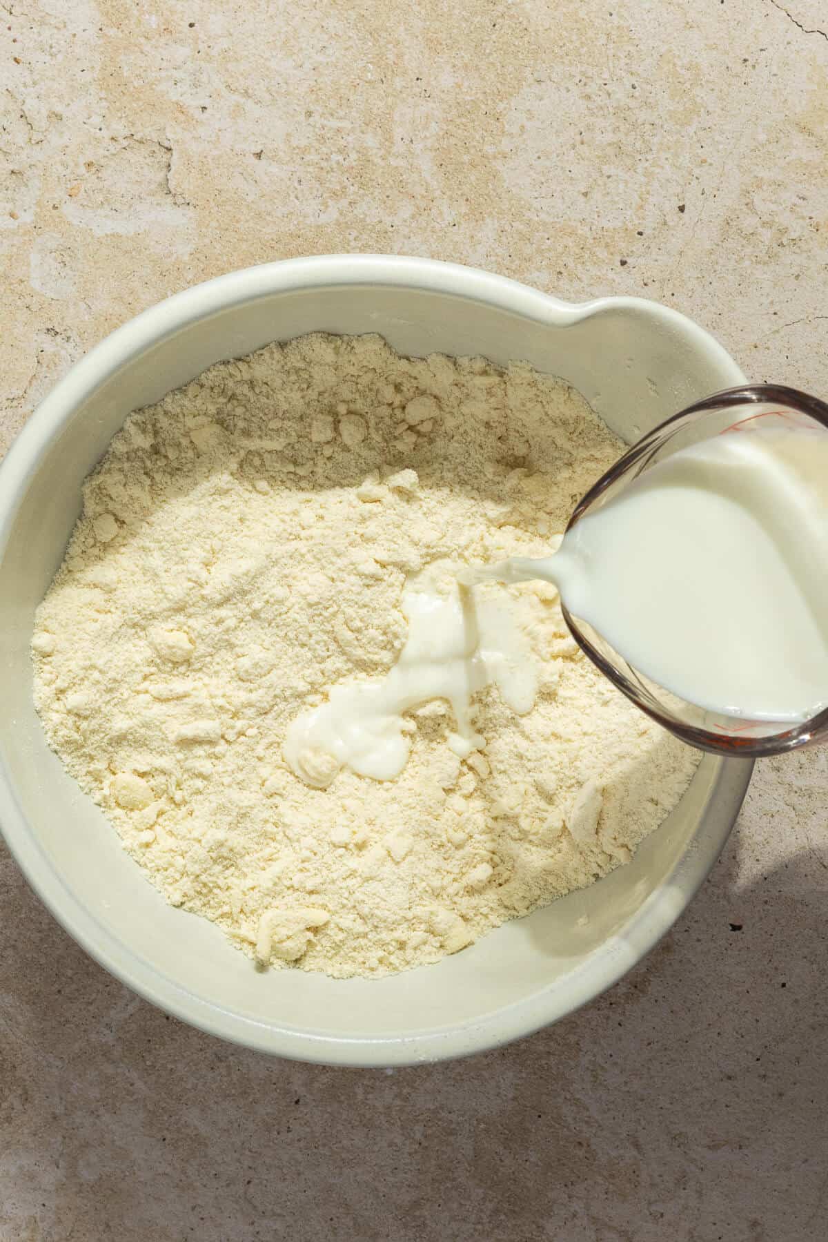 Milk being added to a mixing bowl with the dry ingredients for the shortcakes.