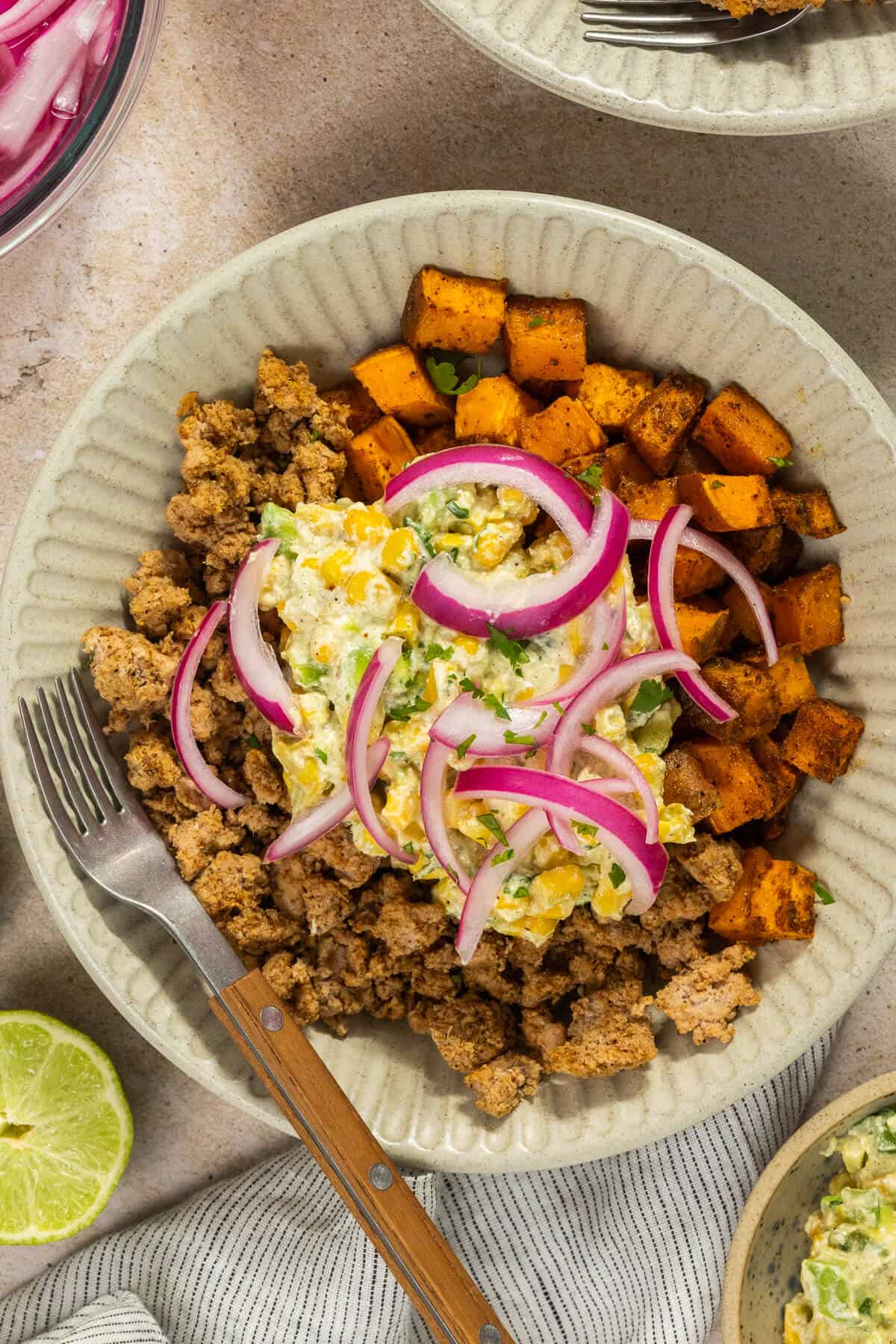 A bowl with the finished street corn bowls topped with pickled onions.