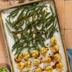 Baked chicken meatballs and green beans on a sheet pan drizzled with homemade sauce.