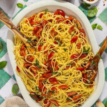 A large platter of bruschetta pasta with serving spoons.