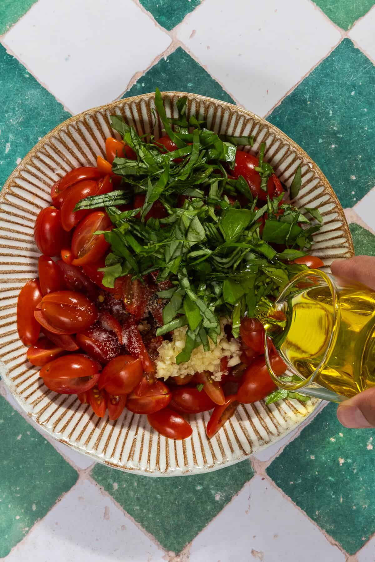 Olive oil being poured into the bowl of the bruschetta ingredients.