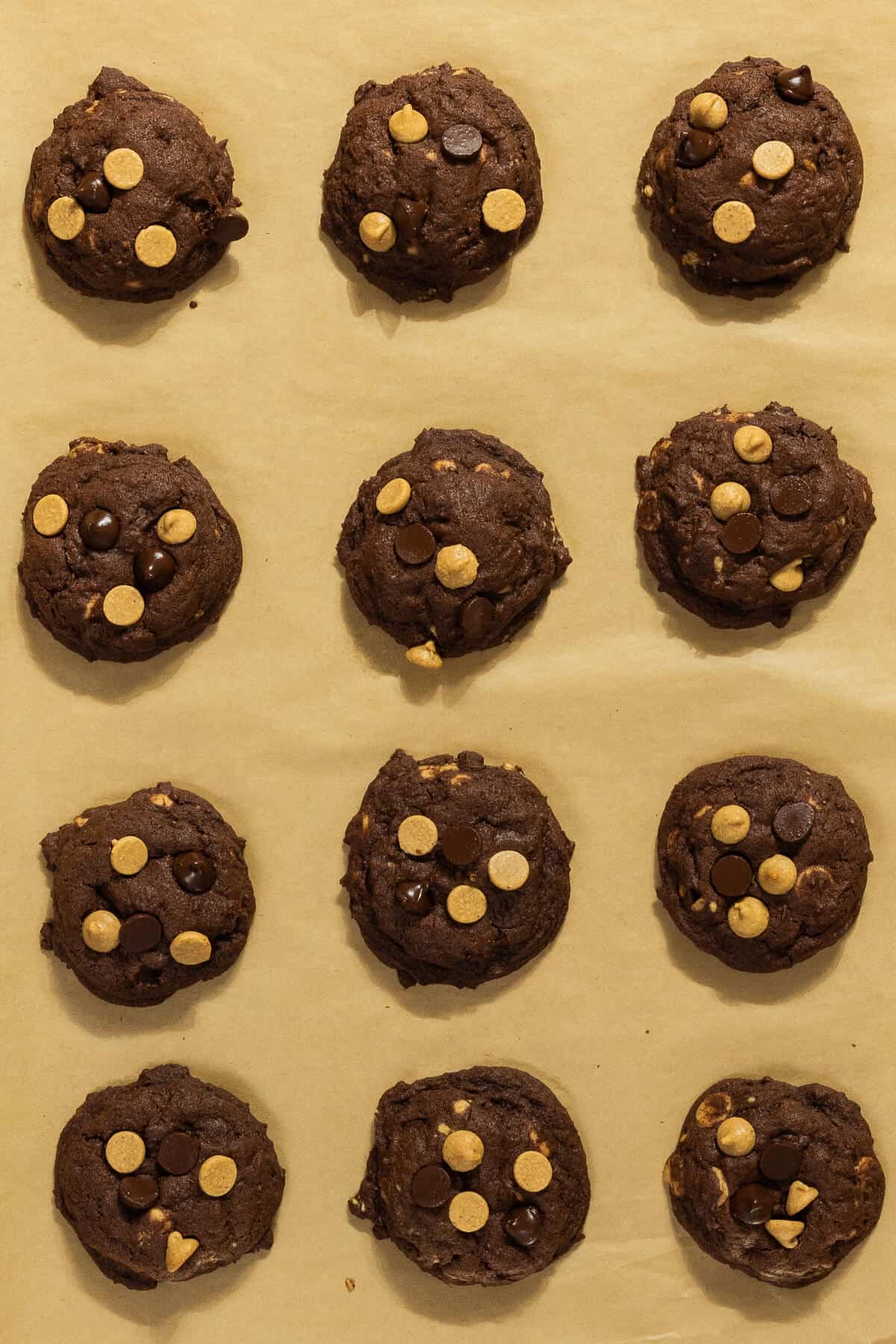 Baked chocolate and peanut butter chip cookies on parchment paper.