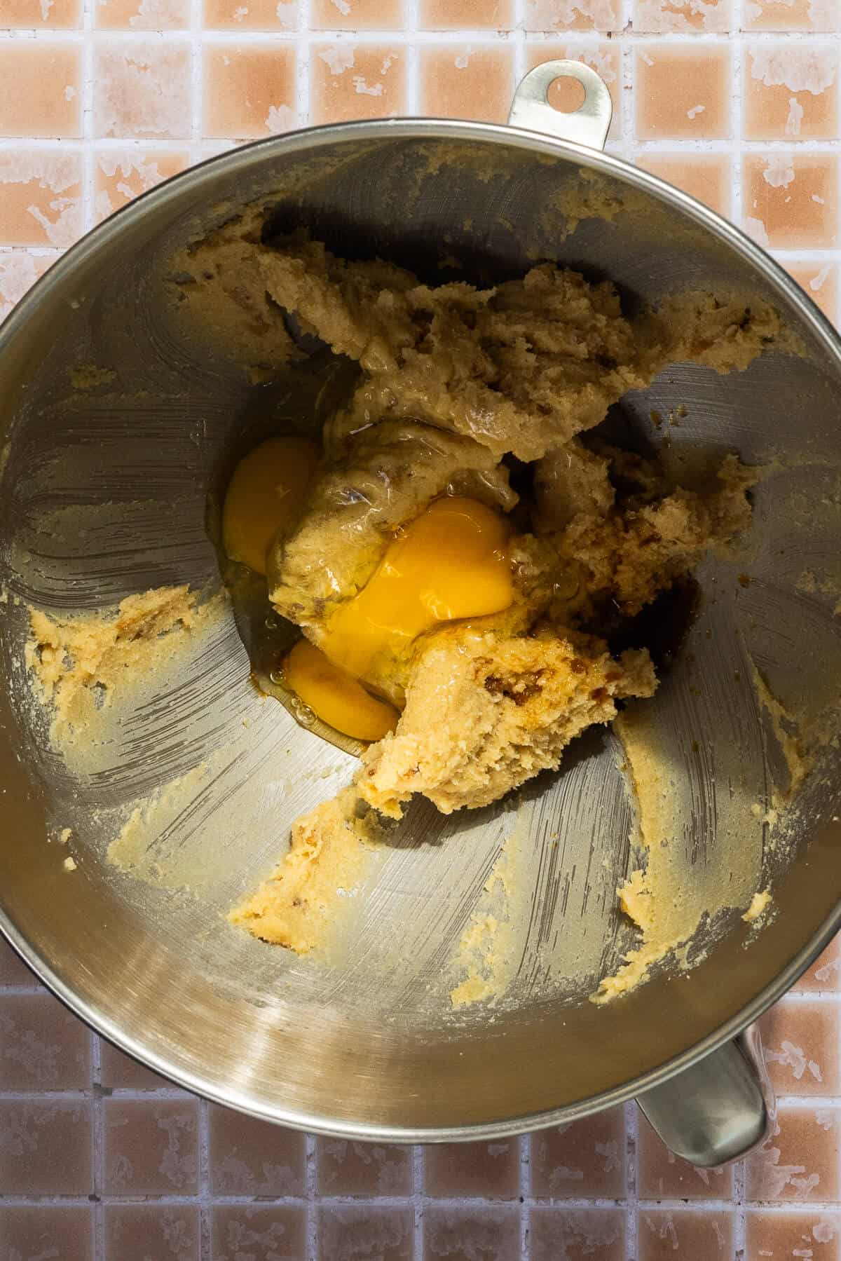 A mixing bowl with eggs and vanilla added to the creamed butter and sugar.