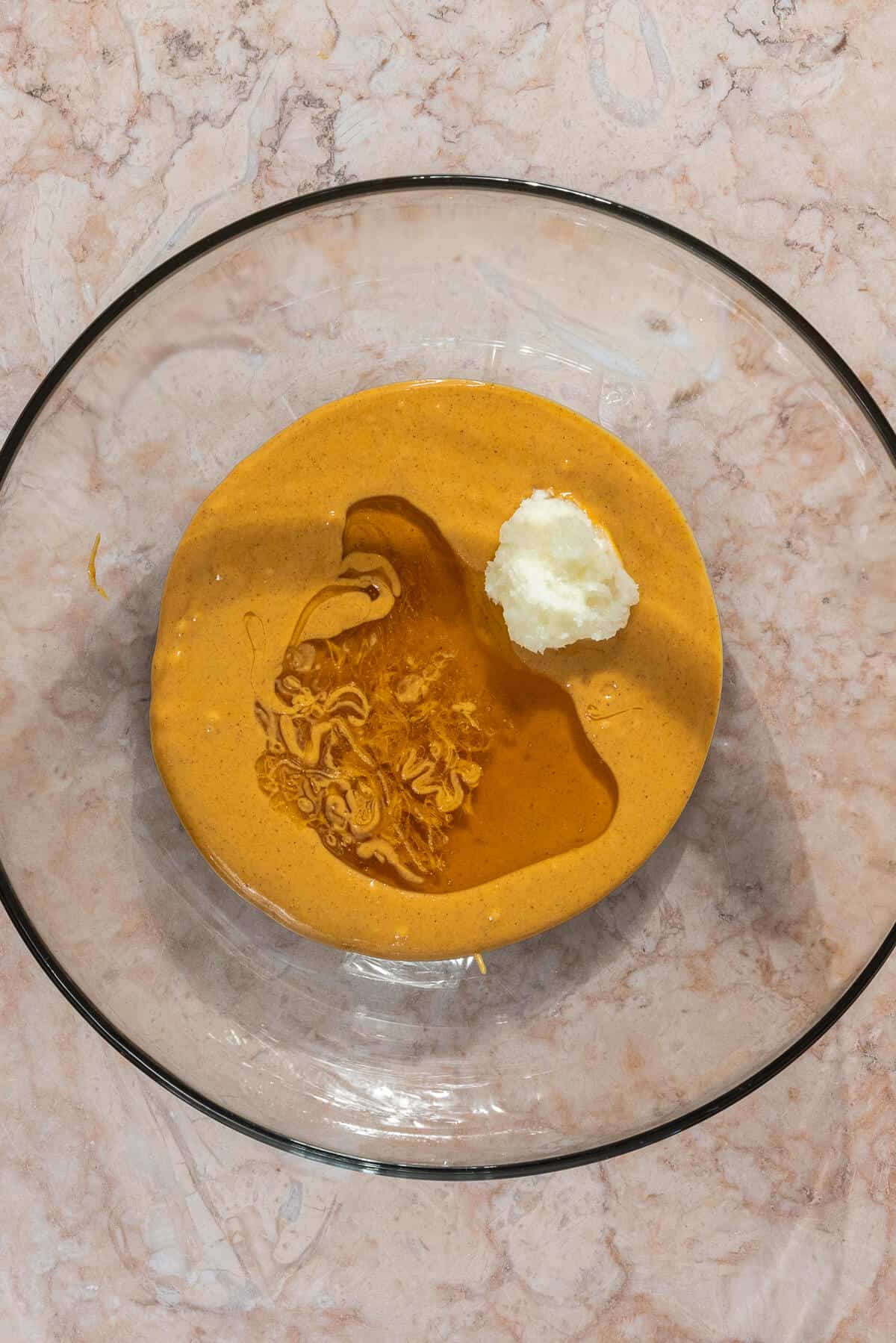 Honey and coconut oil added to a large mixing bowl with peanut butter.