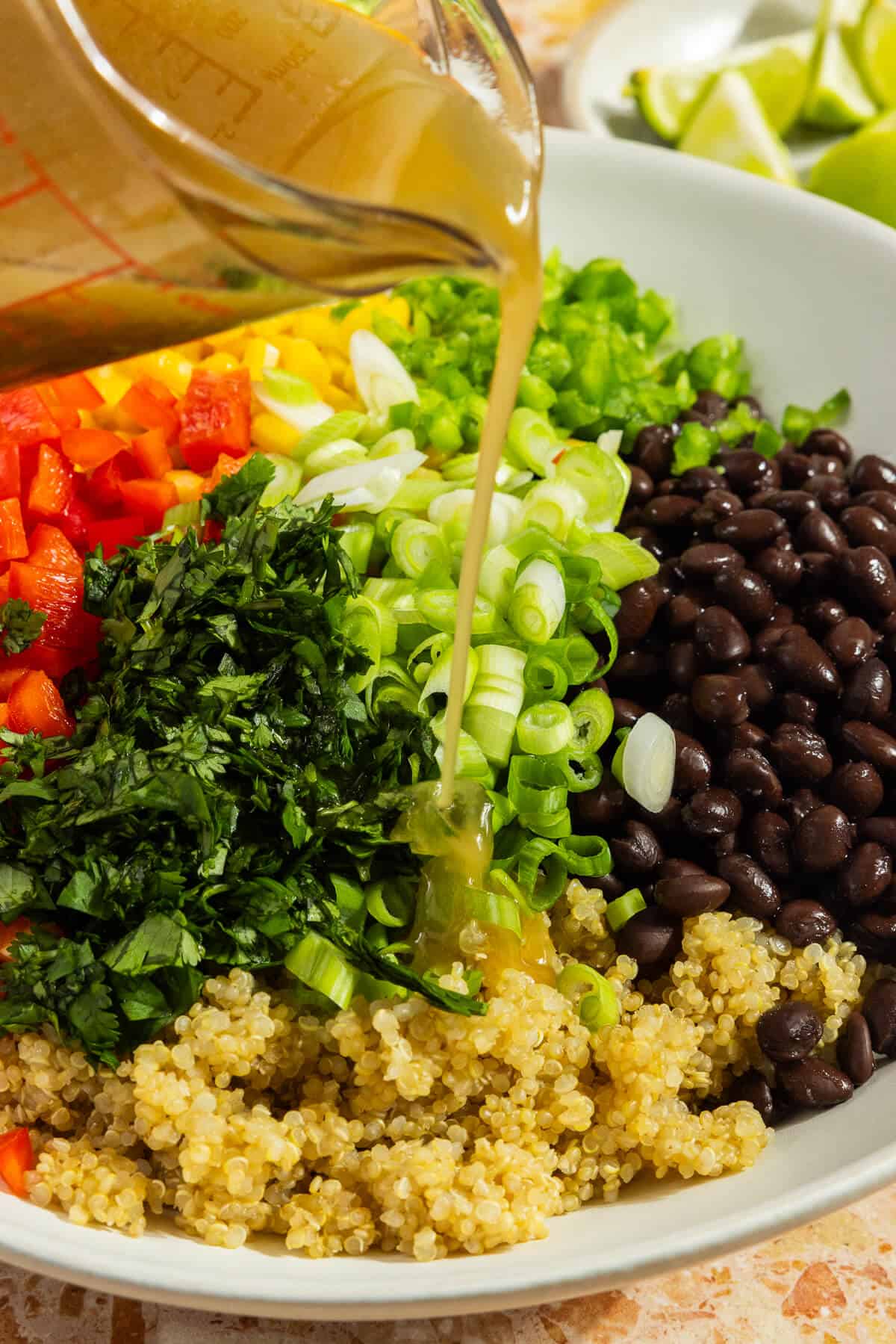 Vinaigrette being poured over the top of the prepared cowboy caviar with quinoa.
