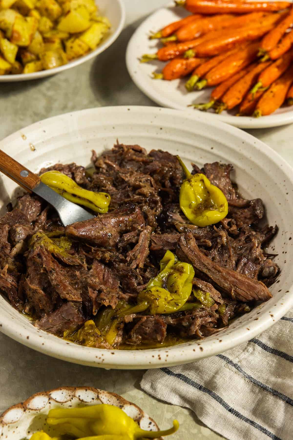 A bowl of prepared Mississippi pot roast served with roasted carrots and potatoes.