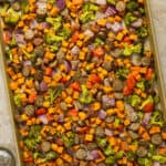A large baking sheet with cooked pesto chicken sausage and veggies sheet pan.