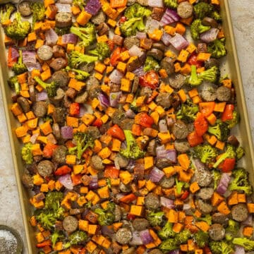 A large baking sheet with cooked pesto chicken sausage and veggies sheet pan.