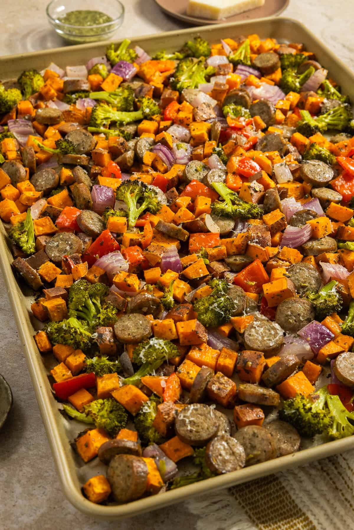 A sheet pan with cooked pesto chicken sausage and veggies sheet pan.