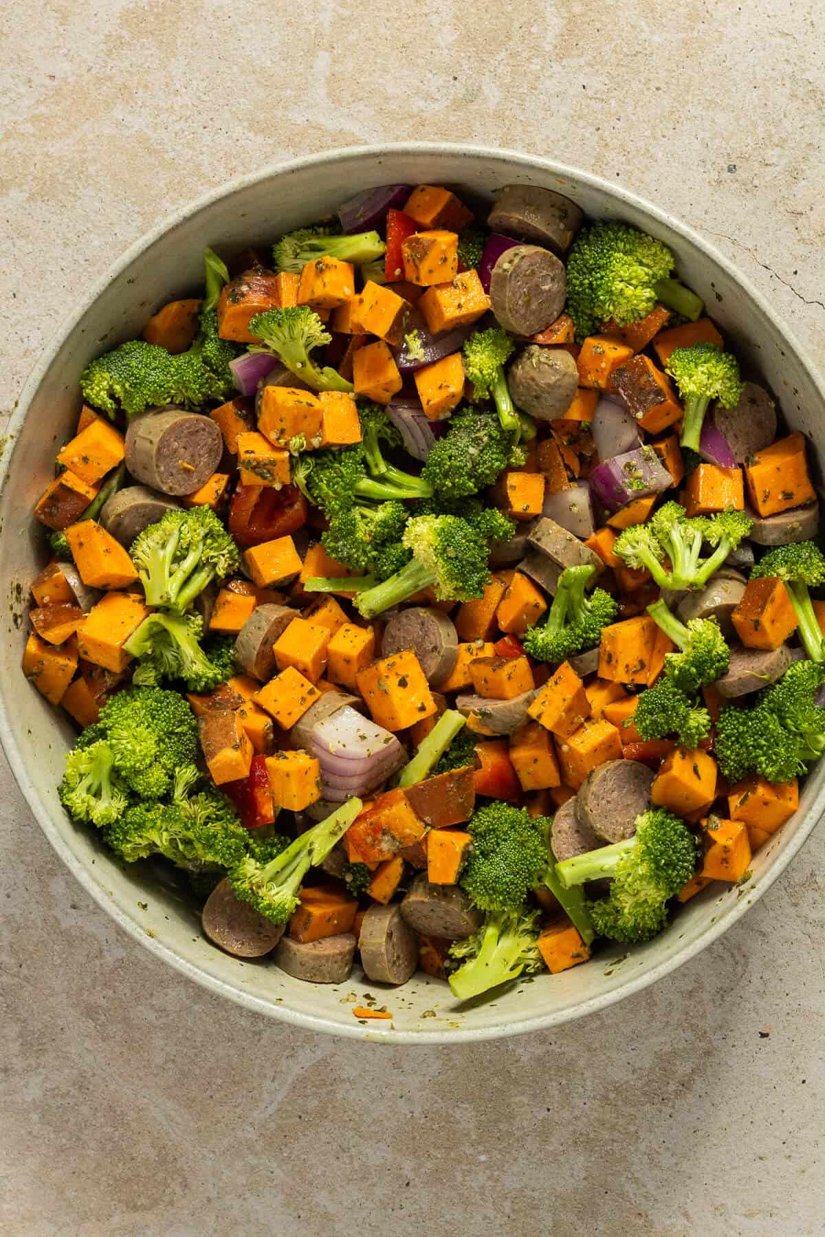 A large mixing bowl with the prepared vegetables and chicken sausage tossed with pesto.