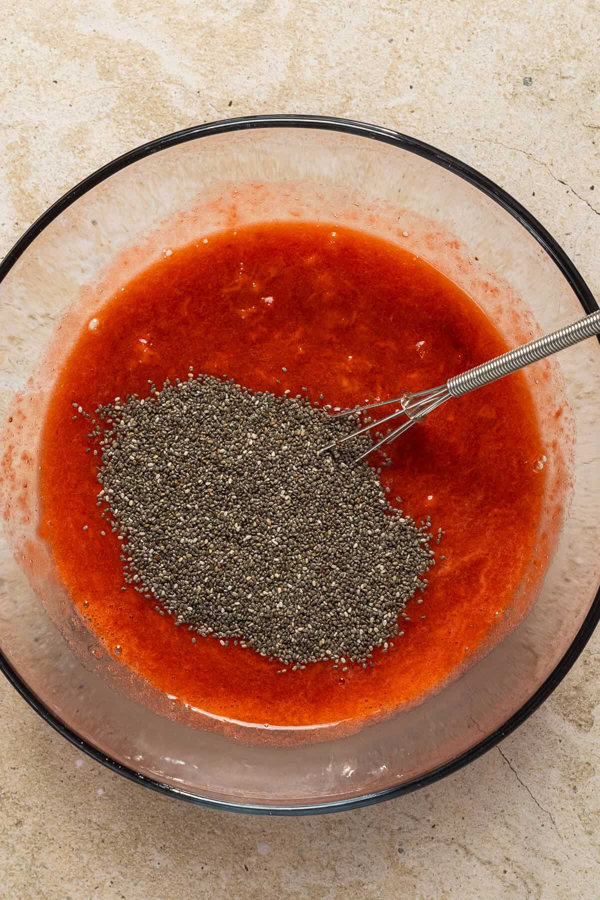 Bowl of chia seeds being mixed into strawberries.