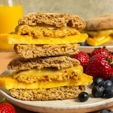 Two sausage breakfast sandwiches stacked on a plate with berries.