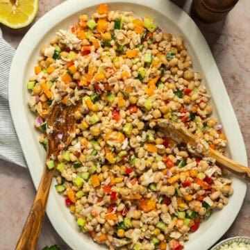 A large platter with the prepared white bean salad and tongs.