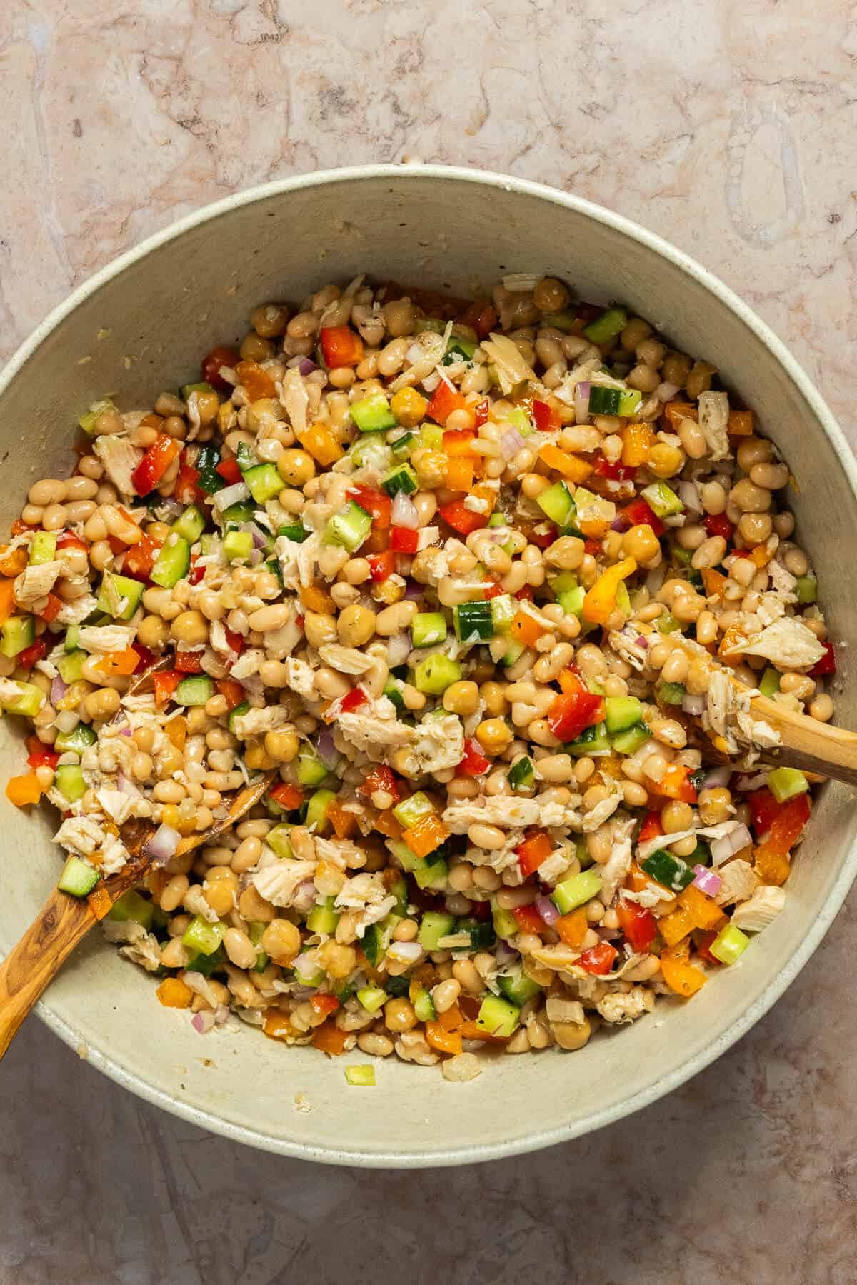 A large mixing bowl of the dressed white bean salad.