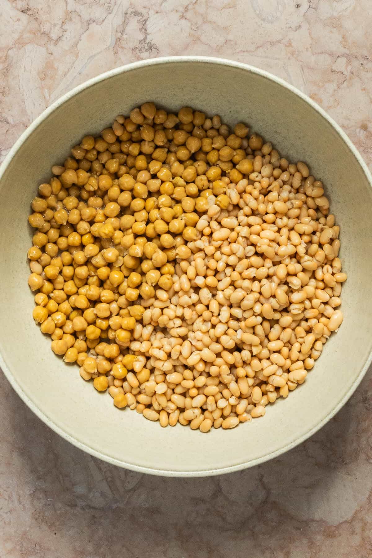 A large mixing bowl with chickpeas and cannellini beans.