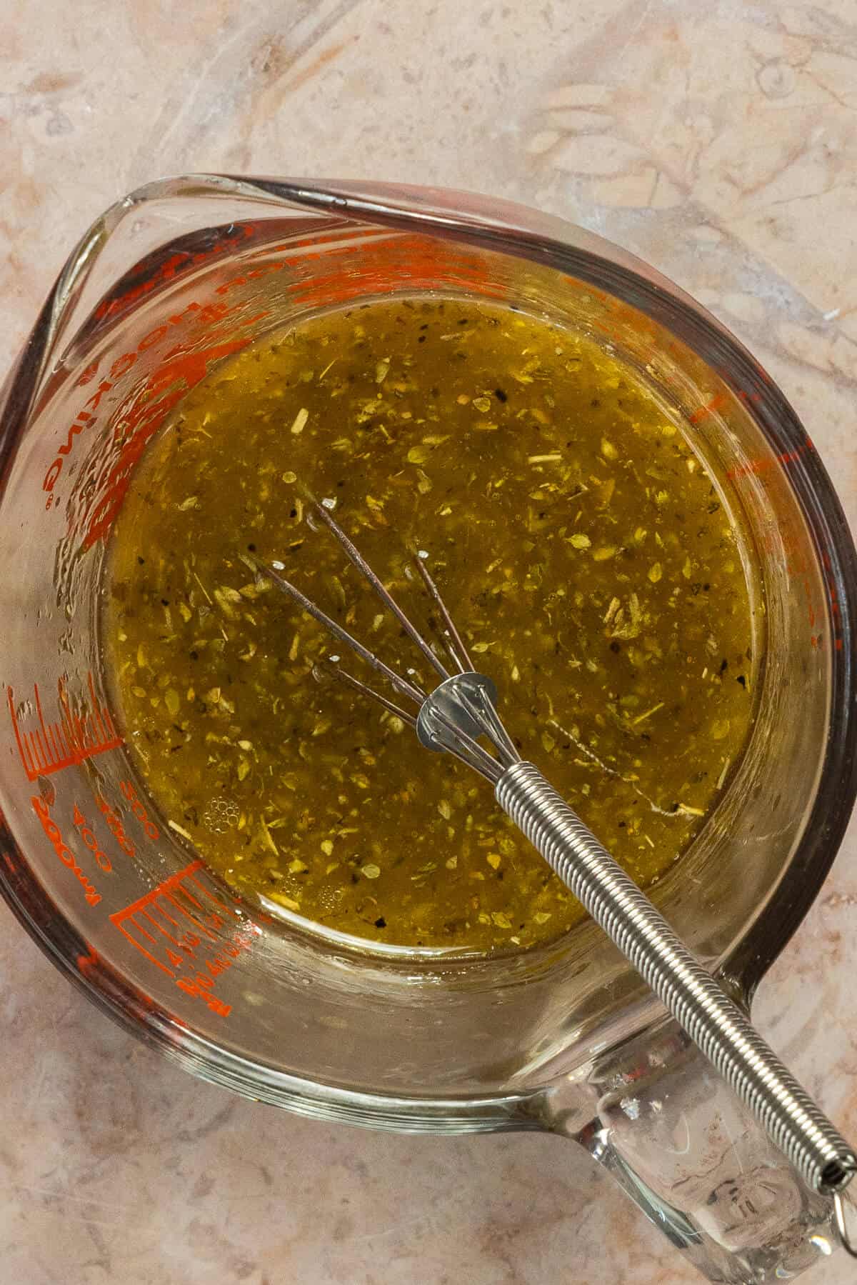 A pyrex measuring glass with the mixed dressing for the mediterranean white bean salad.
