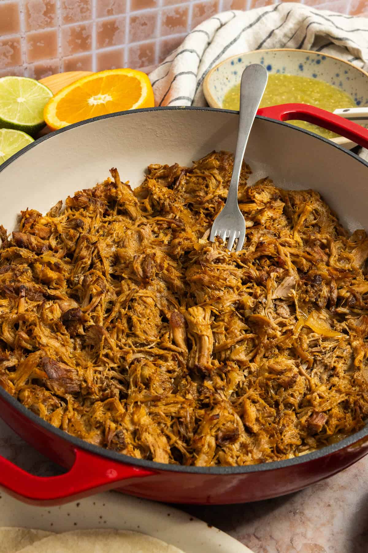 A cast iron pot with shredded slow cooker carnitas.